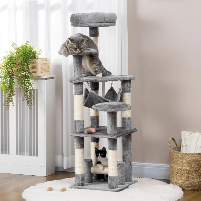 Two cats playing on tall grey cat tree with hammock.