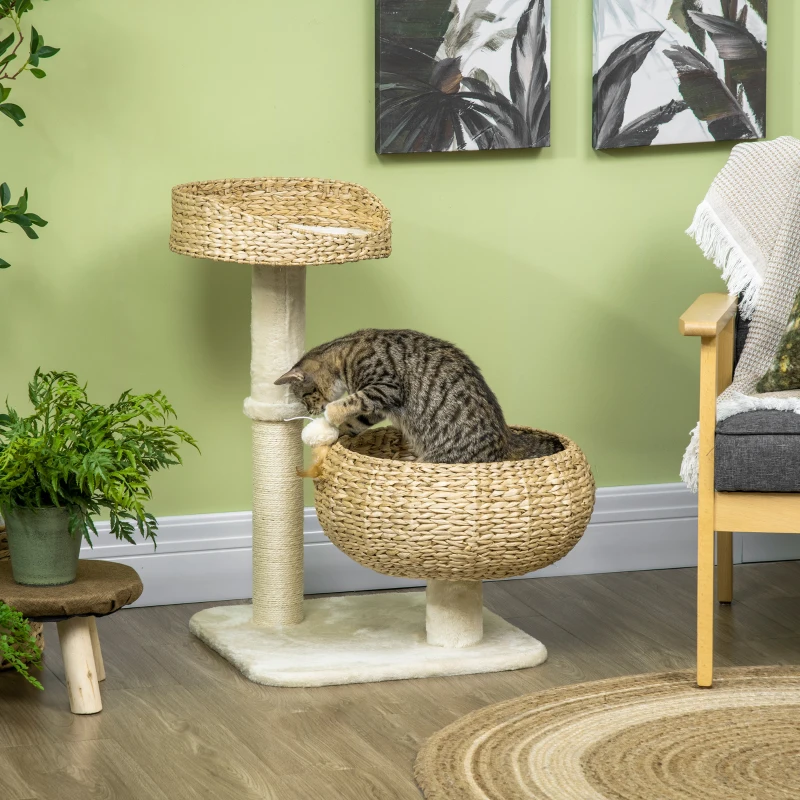 Cat playing on dual woven basket cat tree beside green wall.