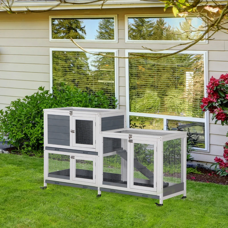 Modern two-tier grey and white rabbit hutch on garden lawn near house windows.