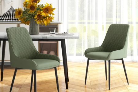 Two green upholstered dining chairs with black legs beside a modern dining table.