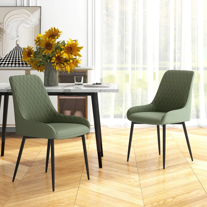 Two green upholstered dining chairs with black legs beside a modern dining table.