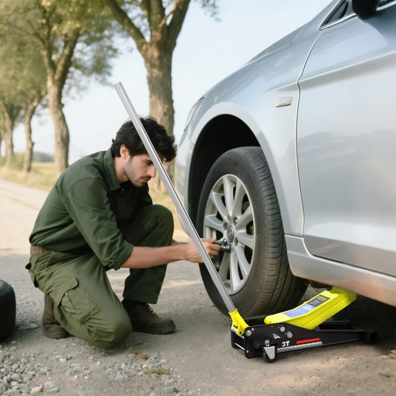 Mechanic changing tire using yellow and black hydraulic floor jack on road.