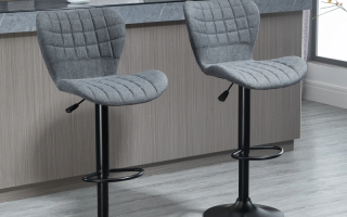 Two grey upholstered bar stools placed at a modern kitchen counter with black metal bases.