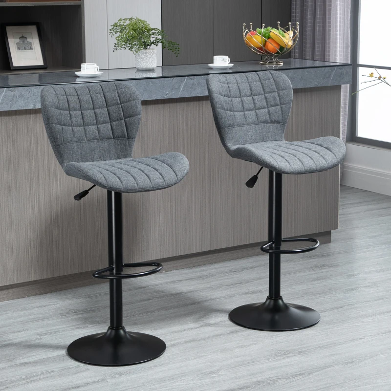 Two grey upholstered bar stools placed at a modern kitchen counter with black metal bases.