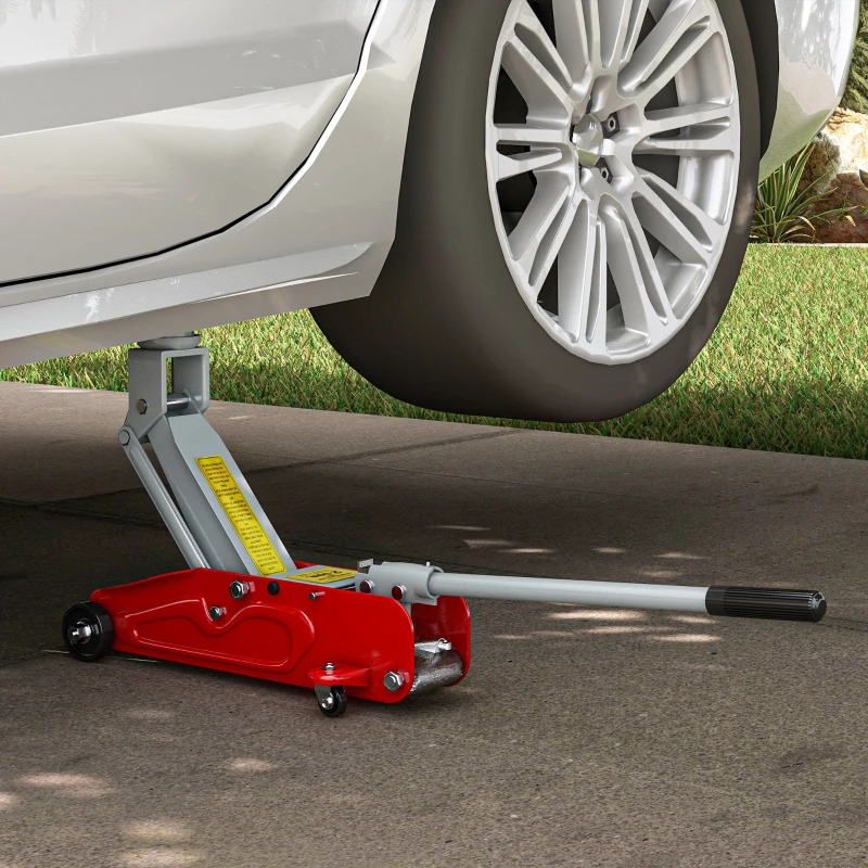 Red hydraulic floor jack lifting white car for maintenance on driveway.