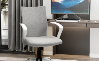 Grey linen mid back office chair with white arms and rolling base near modern desk.