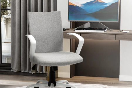 Grey linen mid back office chair with white arms and rolling base near modern desk.