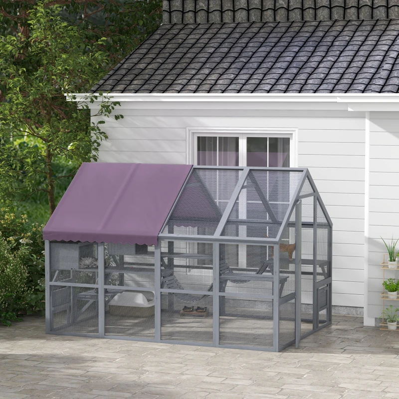 Large grey outdoor cat house with canopy roof and cats playing on multiple platforms.