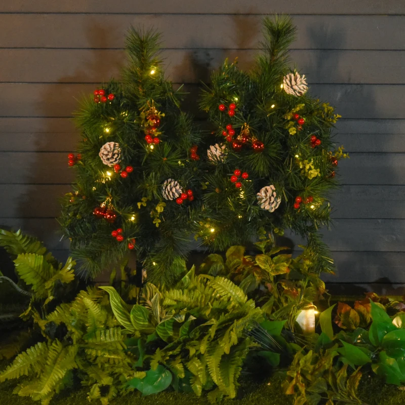 Outdoor Christmas bushes decorated with pinecones, berries, and fairy lights