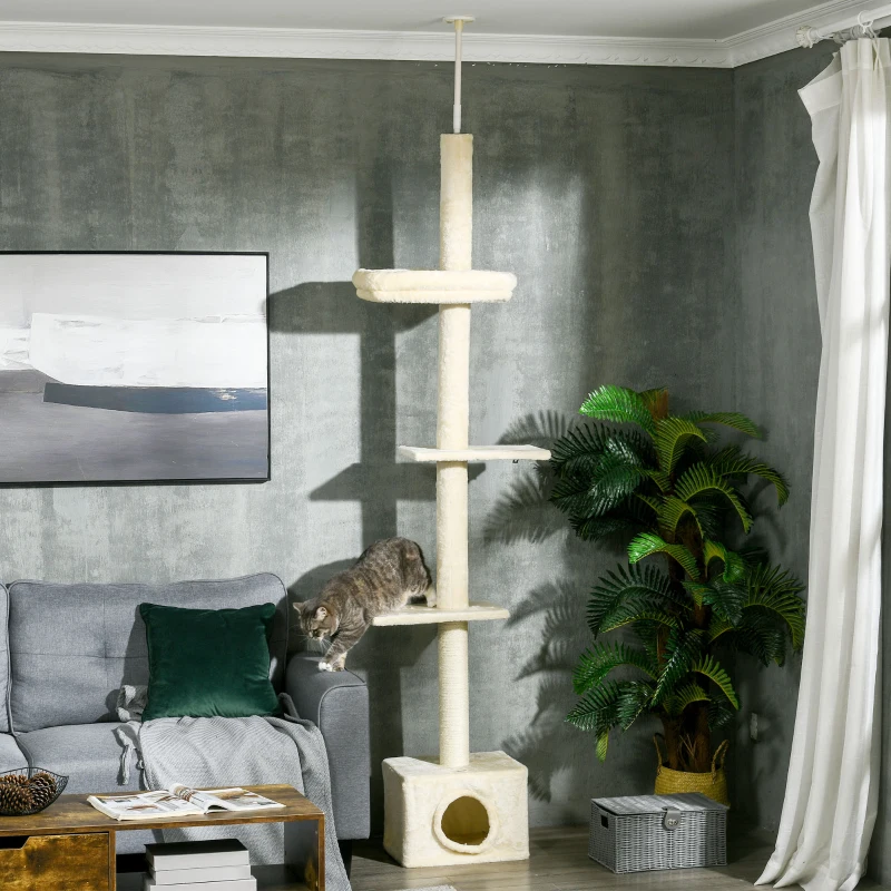 Tall beige floor-to-ceiling cat tower with platforms and a cat climbing from the sofa.