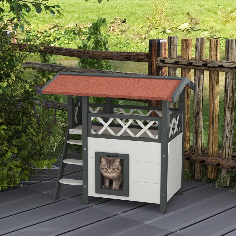 Cat entering small wooden outdoor cat house on deck.