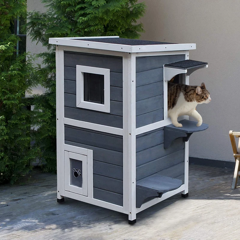 Cat stepping out of multi-level outdoor wooden shelter.