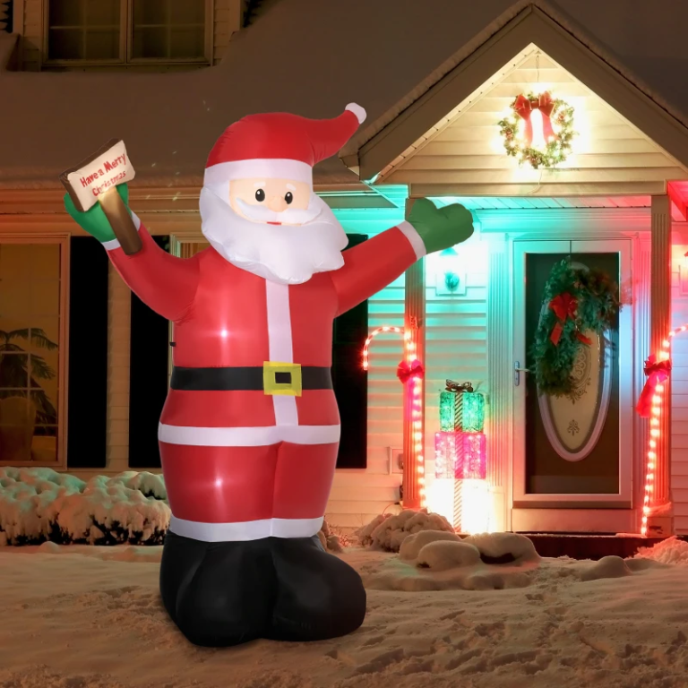 Large inflatable Santa decoration on snowy yard with glowing lights