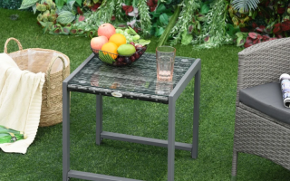 Glass-top rattan table placed outdoors on lawn.