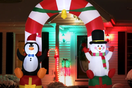 Penguin and snowman inflatable arch lit up at night in snowy yard