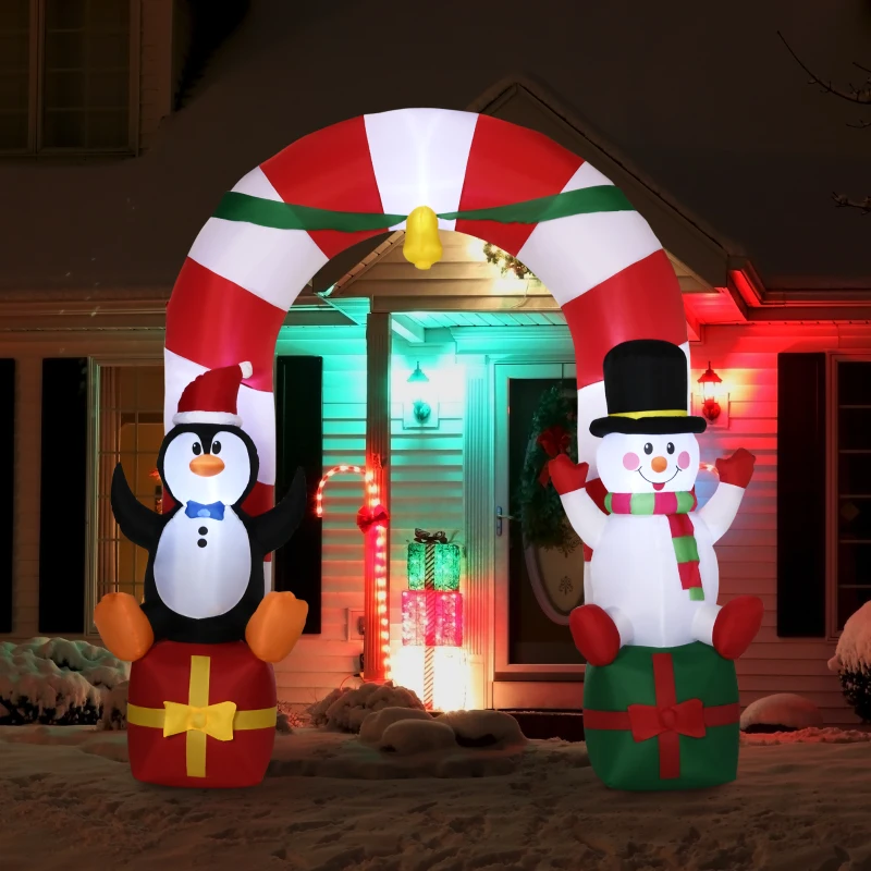Penguin and snowman inflatable arch lit up at night in snowy yard