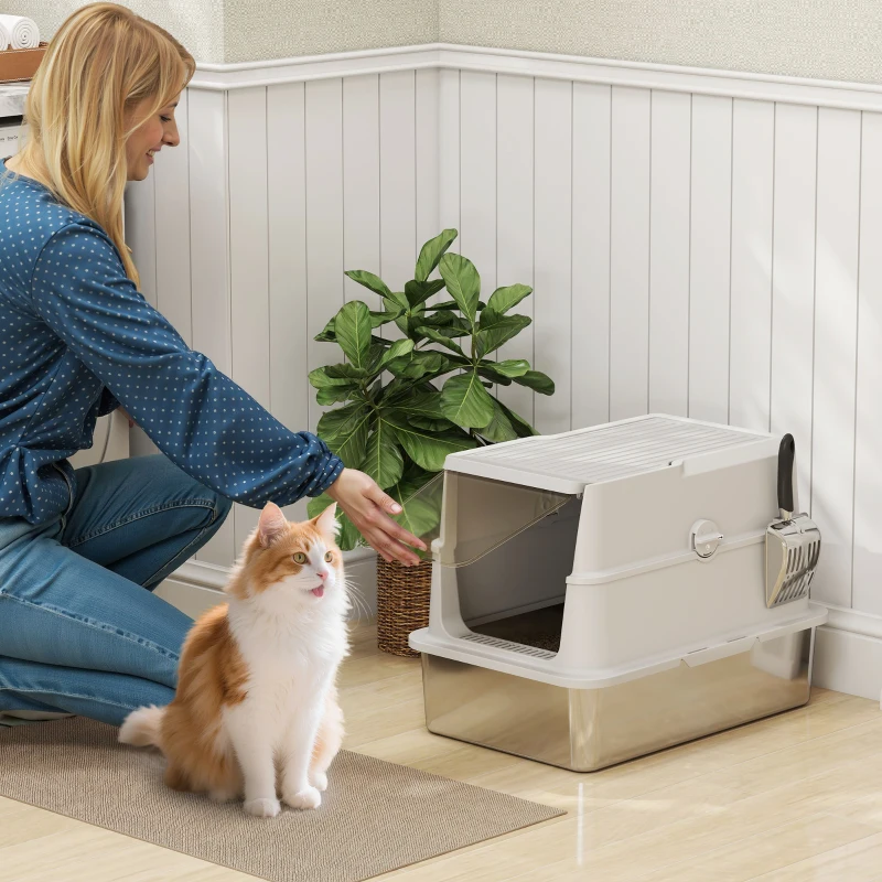 Woman opening enclosed litter box while orange cat sits nearby.