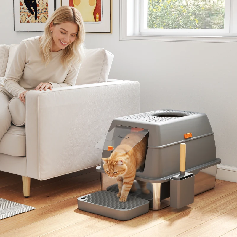 Orange cat exiting grey enclosed litter box with tracking mat.