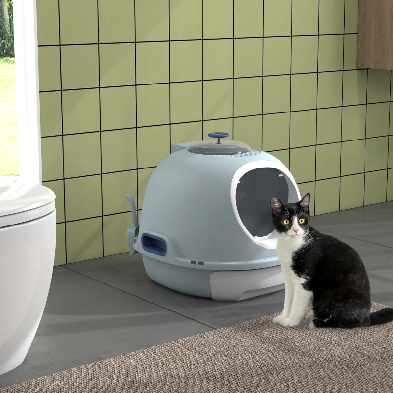 Black and white cat sitting beside dome-shaped litter box.