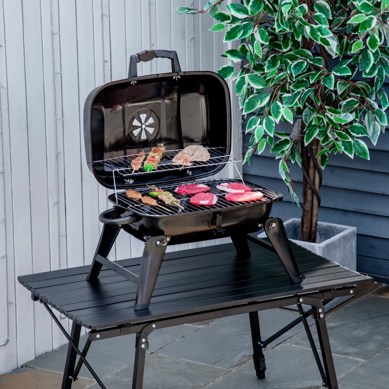 Compact foldable Outsunny charcoal BBQ grill cooking assorted meats on outdoor table.