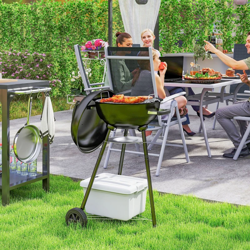 Family enjoying cookout beside classic black Outsunny kettle charcoal BBQ grill on lawn.