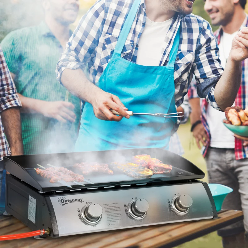 Group of friends cooking on three-burner Outsunny tabletop gas grill during outdoor barbecue.