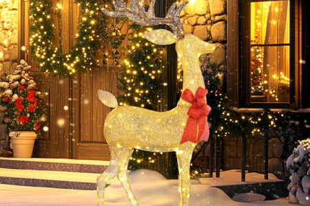 Glowing outdoor Christmas deer with golden lights and red bow in snowy festive garden