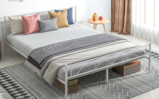 Modern white metal bed frame with layered bedding and throw pillows.