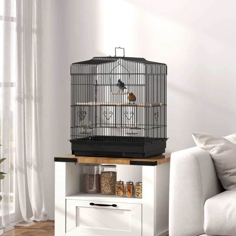 Small bird cage placed on wooden cabinet beside sofa.