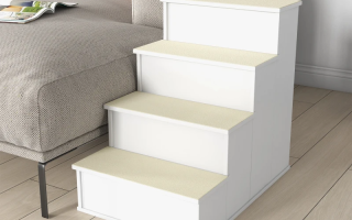 Dog descending white wooden pet stairs beside a large sofa in a bright living room.