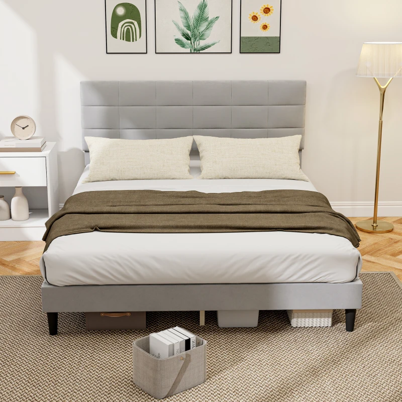 Grey upholstered queen bed with padded headboard and soft neutral bedding in bright room.
