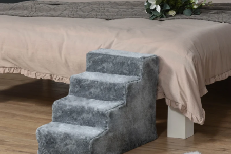 Grey carpeted dog stairs placed beside a bed in a bedroom.
