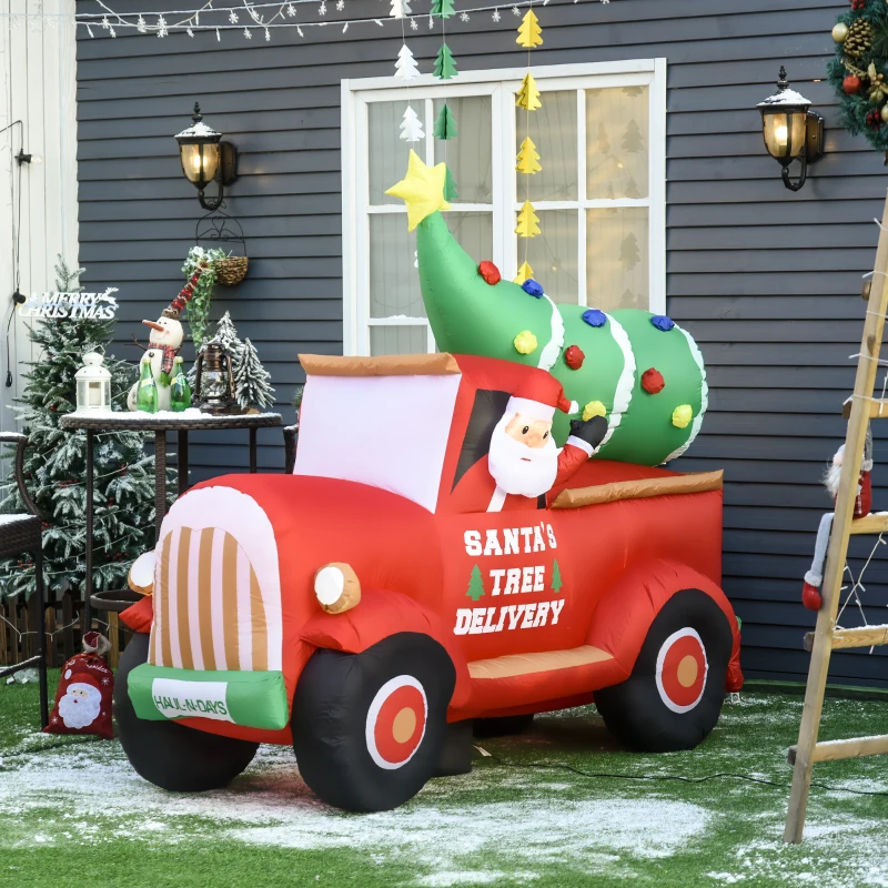 Inflatable Santa driving red truck carrying a decorated Christmas tree in festive yard display.