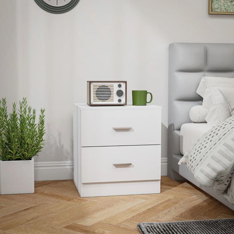 Modern white bedside table beside grey bed with green mug and radio.