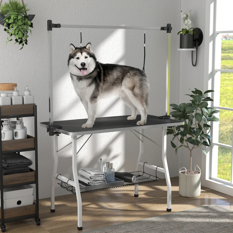 Foldable dog grooming table with black top, dual nooses, storage shelf, and a Husky.