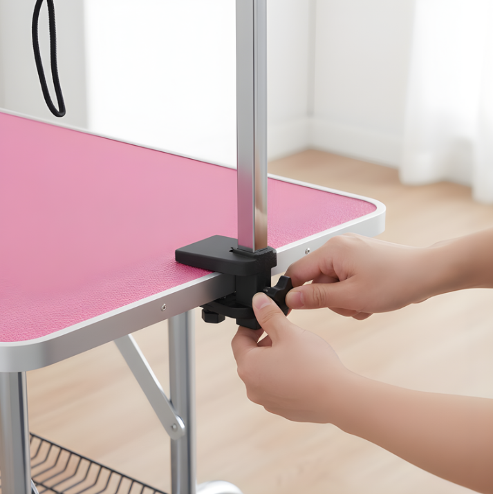 Hands adjusting clamp on grooming arm attached to table edge.