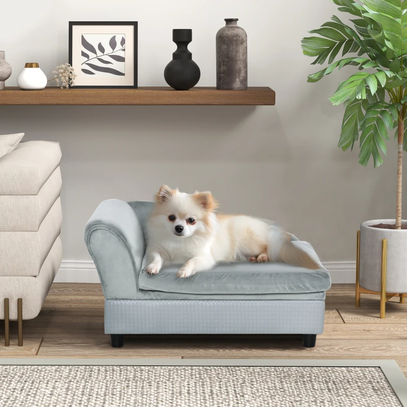  A small fluffy dog resting on a soft grey chaise-style dog sofa in a modern room.