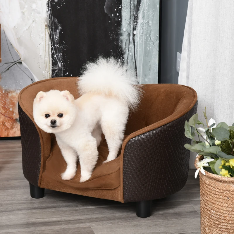 A small brown poodle lying on a grey patterned dog sofa near a window.