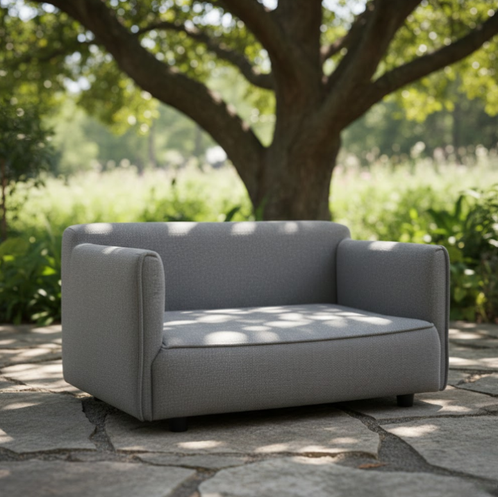 Grey dog couch placed outdoors in shade.