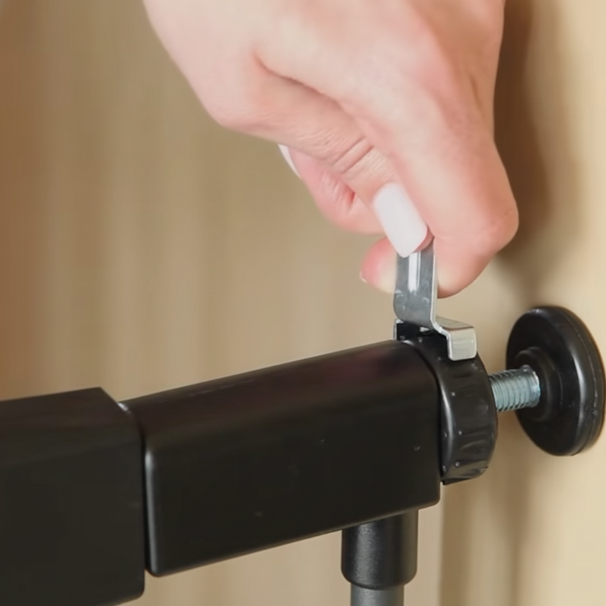 Tightening tension bolts and checking the latch gap for secure pet gate installation.