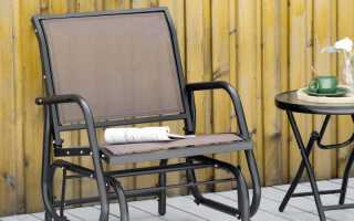 Outdoor mesh patio glider placed beside wooden wall.
