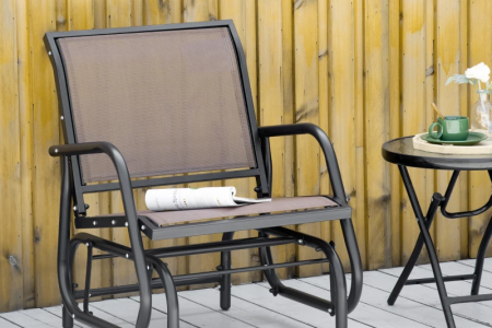 Outdoor mesh patio glider placed beside wooden wall.