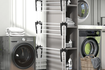 Foldable clothes drying rack placed in a laundry room beside washer and shelves.