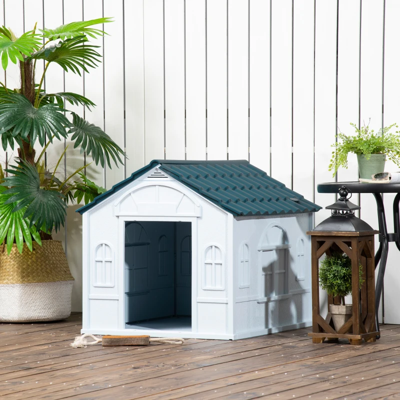 Outdoor plastic dog house placed on a wooden deck near plants and decor.