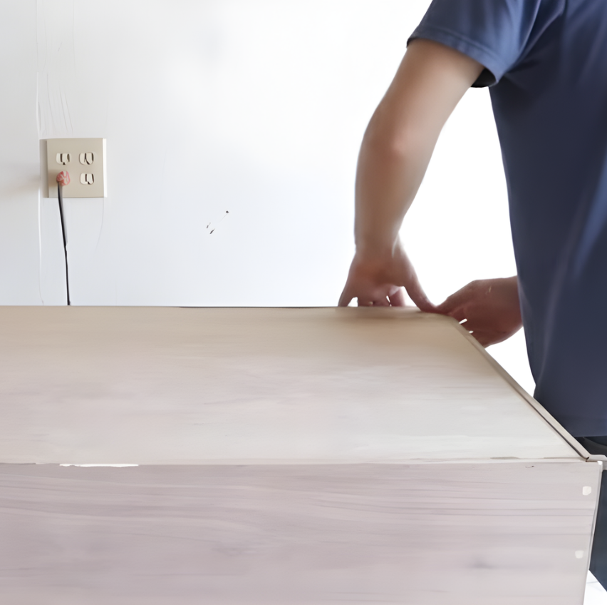 Attaching a plywood bottom panel to the dog bed frame with glue.