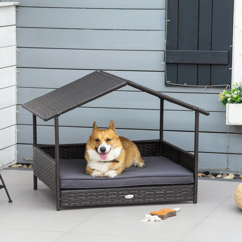 Corgi resting on outdoor rattan dog bed with canopy.